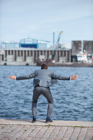 The temptation to quit is strongest before you succeed. Full length shot of an unrecognizable businessman standing on the dock and wanting to jump into the water.の写真素材