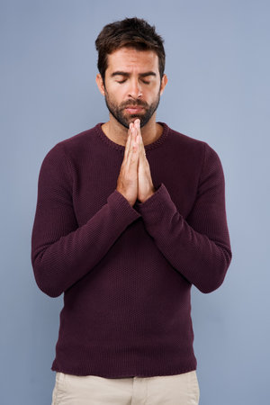 Dear God...Studio shot of a handsome young man praying against a gray background.の写真素材