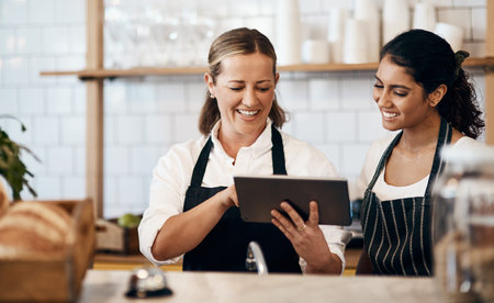 Modern tech makes them a more productive team. two women using a digital tablet together while...