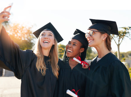 Friends, students and graduation selfie with college or university women together with a smile. People outdoor to celebrate education achievement, success and future at event for school graduatesの写真素材