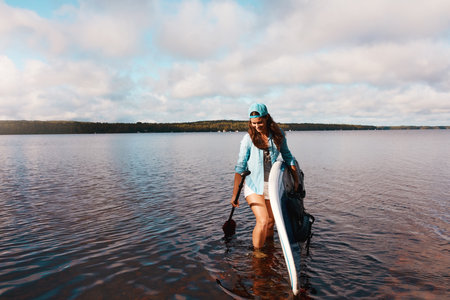I love being in the water. a young woman paddle boarding on a lake.の写真素材