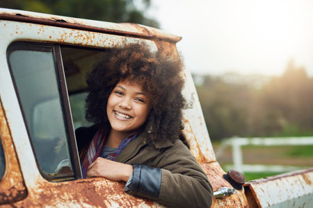 Life is a journey. Portrait of a happy young woman sitting in a rusty old truck.の写真素材