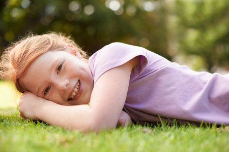 Summer is finally here. A smiling girl lying in the grass outside.の写真素材