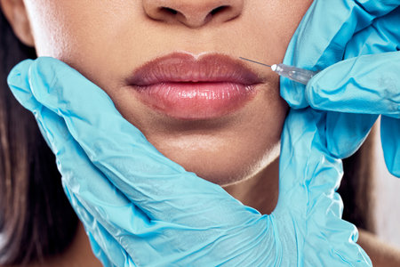 Erasing all fine lines. a woman having her lips injected with filler against a studio background.の写真素材