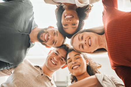 Portrait of businesspeople huddled together. Diverse group of businesspeople from below. Happy corporate coworkers from below. Architects smiling from below. Professional businesspeople togetherの写真素材