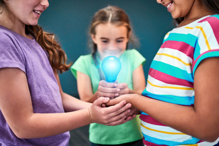 Kids power the world. Studio shot of a group of kids holding a lightbulb together against a blue background.の写真素材