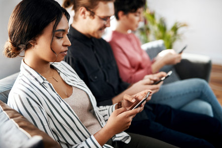 Technology helps kill the waiting time. a diverse group of businesspeople sitting in the office...
