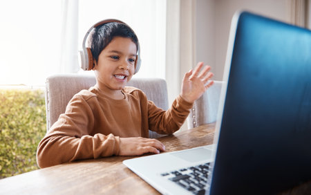 Elearning, wave and kid on laptop video call with headphones for education or studying. Development, growth and happy boy waving on computer for greeting in virtual or online class for homeschool.の写真素材