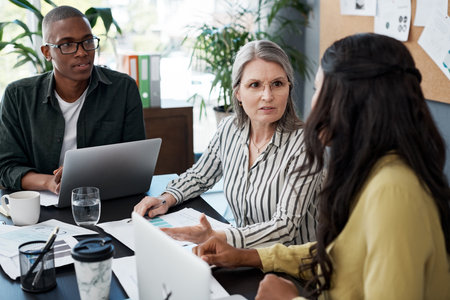Definitely something between us, I believe its a misunderstanding. a group of businesspeople brainstorming and using a laptop in a modern office.の写真素材
