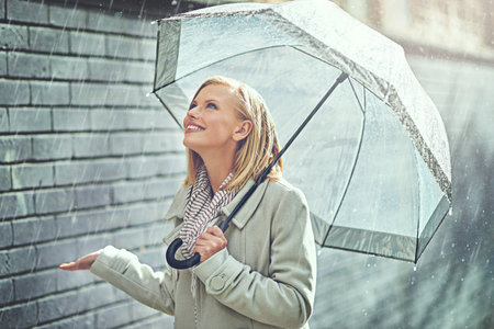 Rain umbrella, city street and woman smile with happiness on a sidewalk from winter weather. Happy female person, raining and travel on a urban road in New York on holiday with freedom and joyの写真素材