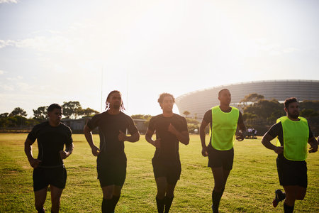 Getting our muscles moving. a diverse group of sportsmen warming up before playing rugby during the day.の写真素材