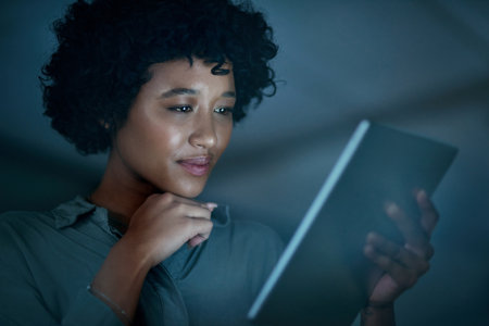 Turn up the focus for full on productivity. a young businesswoman using a digital tablet during a late night at work.の写真素材