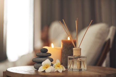 Spa, aromatherapy and candles on table for zen, calm and peace to relax for health and wellness. Stones, flowers and diffuser for self care, holistic massage and hospitality at a beauty salonの写真素材
