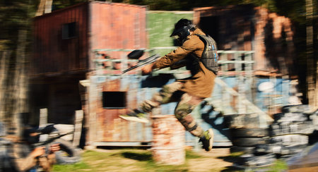Paintball, man jump and aim gun at target, military tactics at shooting range and war game for sports outdoor. Soldier with weapon on battlefield, action and camouflage, motion blur and adventureの写真素材