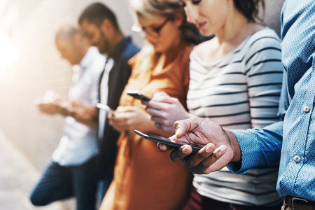 Social media, communication and phone with hands of people for networking, internet and connection. Technology, contact and search with friends at wall in city for website, online and appの写真素材