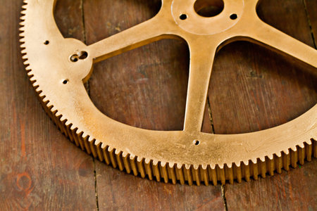 Clock gear, gold and wheel cog on a wood table with golden machinery and gears. Metal, closeup and...