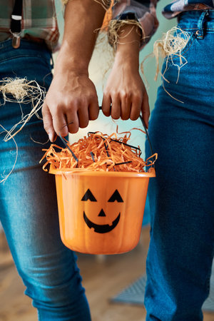 In the mood for some trick-or-treating. two unrecognizable people holding a bucket at home.の写真素材