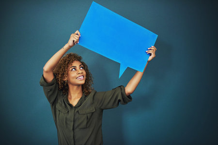 Giving you a voice. Studio shot of a woman holding a speech bubble against a blue background.
