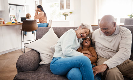 Laughing, happy and grandparents babysitting a child, bonding and being funny on the sofa. Smile, comic and boy kid speaking to a senior man and woman on the living room couch for quality timeの写真素材