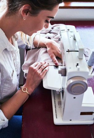 I have a need to create. a young fashion designer using a sewing machine in her workshop.の写真素材
