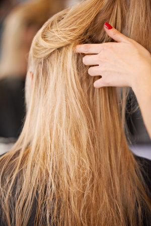 Her hairs looking good. Rear view of a young woman having her hair styled by a hairdresser.の写真素材