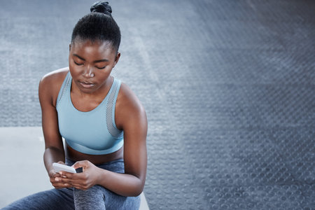 I missed a few calls during my workout. a fit young woman using her cellphone while at the gym.