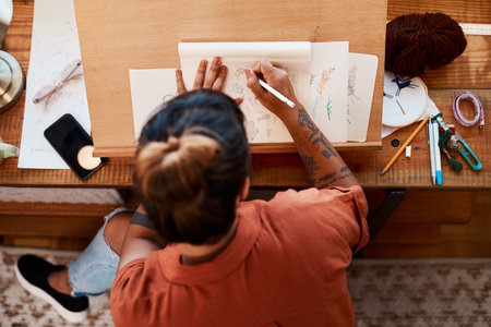 Im always busy on something new. a young woman sketching at home.の写真素材