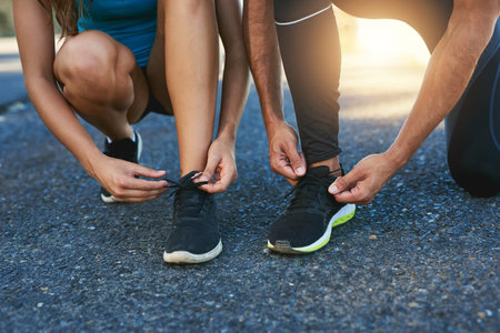 Tie up and hit the road together. a couple tying their shoelaces while out for a run.