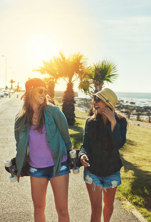 Summer is about skateboarding. two friends hanging out on the boardwalk with a skateboard.の写真素材