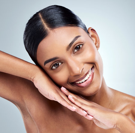 Happy, skincare and portrait of Indian woman with beauty cosmetic isolated in a studio white background. Clean, natural and female person or model hand on her face for self love, dermatology or careの写真素材