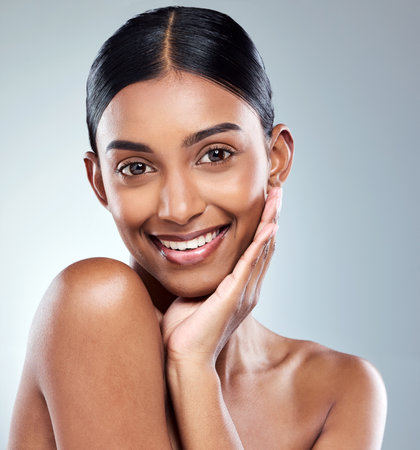 Smile, portrait and Indian woman beauty or model with skincare cosmetic isolated in a studio white background. Clean, natural and female person hand on face happy for self love, care or dermatologyの写真素材