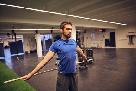 I do not put limits on myself. a handsome young man working out with a stick in the gym.