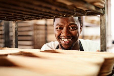 Off to the oven we go. a male baker pushing a baking trolley.の写真素材