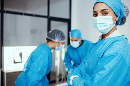 Medical, surgeon or doctor in scrubs and face mask in hospital with staff working during covid virus crisis for health and wellness with safety. Portrait of a woman with arms crossed for healthcareの写真素材