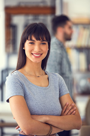 Our business is on the grow daily. Portrait of a confident young businesswoman with her colleagues working in the background of a modern office.の写真素材