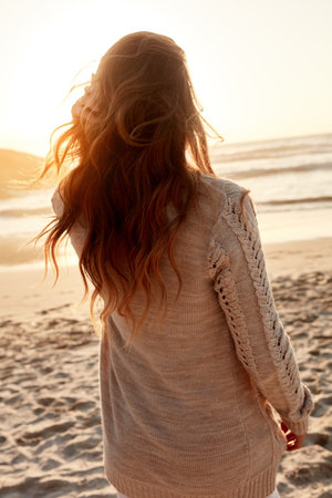 Theres so much beauty out here. Rearview shot of a young woman spending some time at the beach.の写真素材