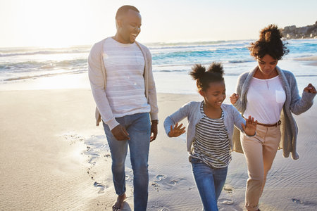 Walks with the fam along the coast. an adorable little girl going for a walk with her parents on the beach.の写真素材