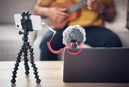 Laptop, phone and music influencer, man with ukulele on sofa, webinar recording and live streaming...