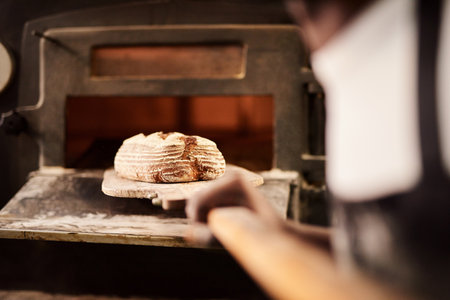 Fresh from the oven. a male baker removing freshly baked bread from the oven.の写真素材