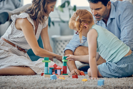 Family, building blocks and girl playing or learning in home, having fun and bonding with parents. Development, love and support of caring father and mother with kid enjoying toys together in house.の写真素材