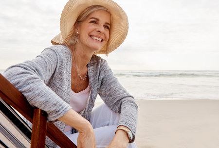 Its blissful at the beach. an attractive middle aged woman sitting on a lounger at the beach.