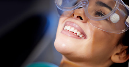 Feels good to smile again. a young woman wearing goggles during a dental procedure.の写真素材
