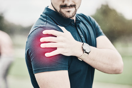 Sports, shoulder pain and man on golf course holding arm during game massage and relief in health and wellness. Green, zoom on hands on muscle for support and golfer with ache during golfing workout.の写真素材