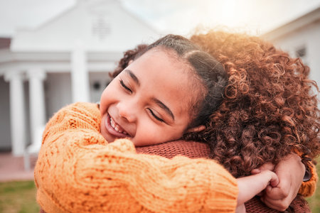 Hug, happy and smile with mother and daughter for bonding, affectionate and care in outdoors. Relax, happiness and support with woman and young girl on lawn of home for embrace, cuddle and weekendの写真素材