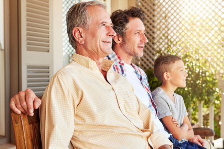 Looking to the future of their family. a young boy sitting outside with his father and grandfather.