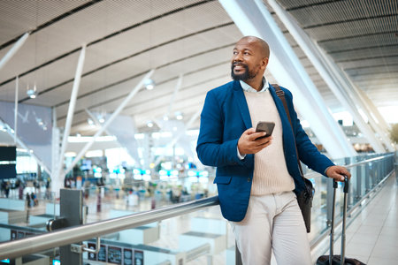 Black man waiting in airport with phone, smile and luggage in terminal for business trip. Technology, travel and happy businessman with international destination checking flight schedule app online.の写真素材