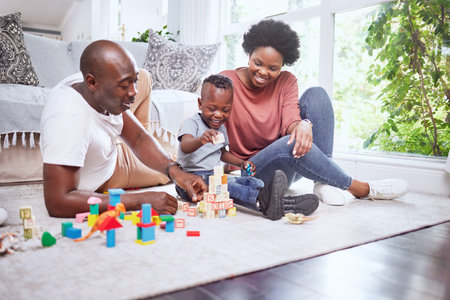Toys, building blocks and black family playing on a living room floor happy, love and bonding in their home. Child development, learning and kid with parents in a lounge with alphabet, shape and gameの写真素材