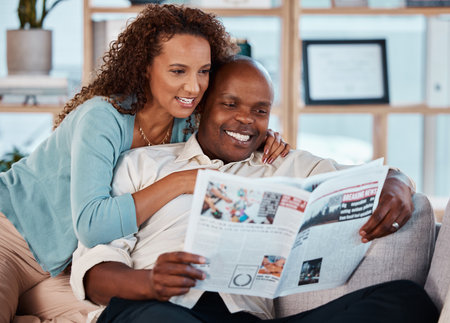 Couple, happy and reading newspaper in home, living room and check article information. Man, woman and smile in house with local magazine, print media and knowledge of international news in paperの写真素材