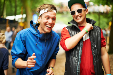 Good friends and good times. two friends drinking beer and having a good time at an outdoor music festival.の写真素材