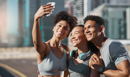 Phone, selfie and fitness with a man and woman sports group taking a photograph together in the city. Health, teamwork and mobile with an athlete group posing for a picture in an urban townの写真素材